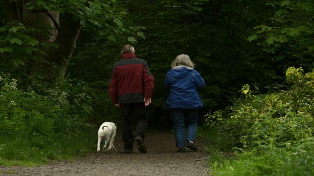 A mature couple walking with their dog