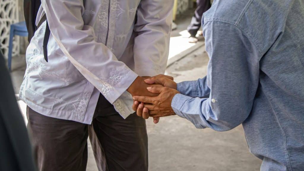 Two people in long-sleeved shirts grasp each other's hands.