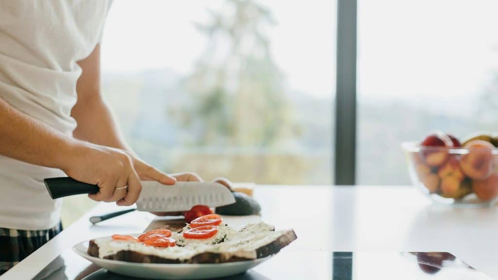 A person slicing tomato on bread.