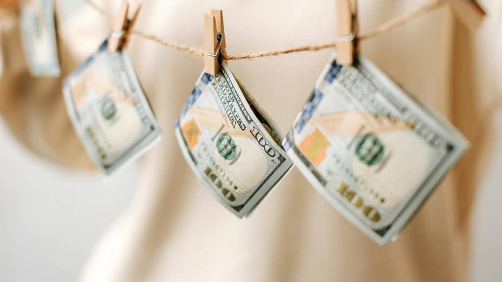 A string of $100 bills clipped to twine with wooden clothespins.
