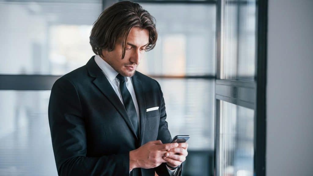 Man in a suit texting on his phone