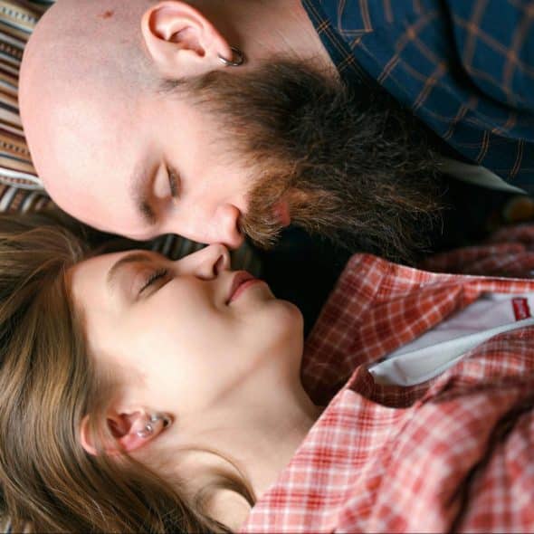 A man and woman laying at the bed.