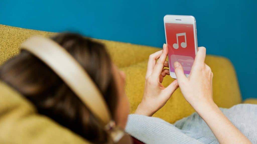 A person wearing headphones selecting music on a smartphone.