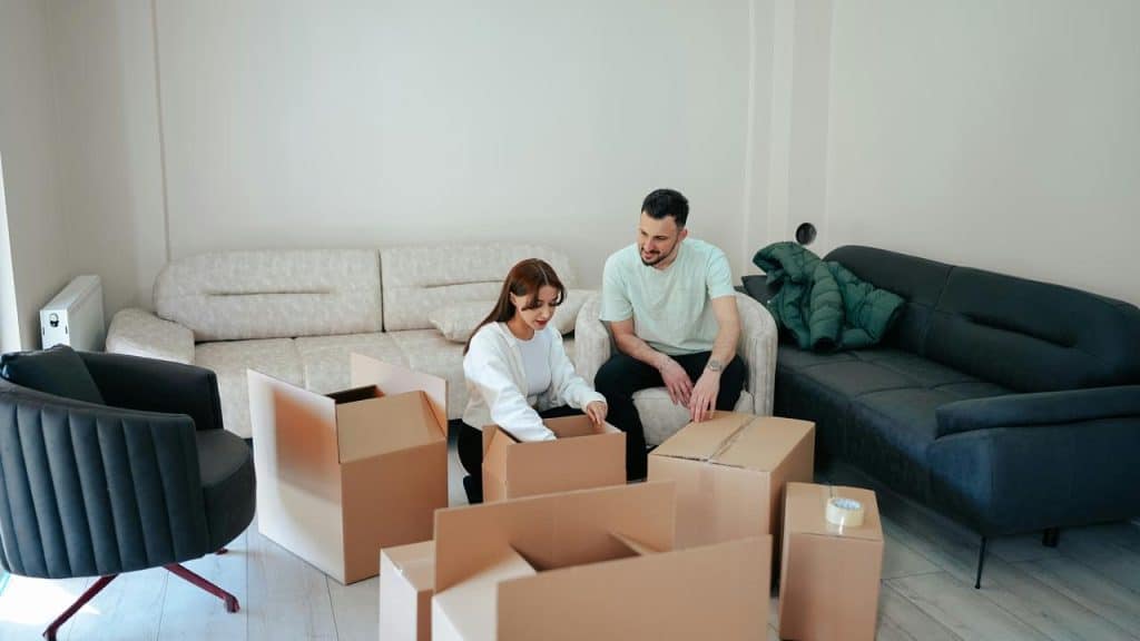 A couple unpacking boxes in a living room.