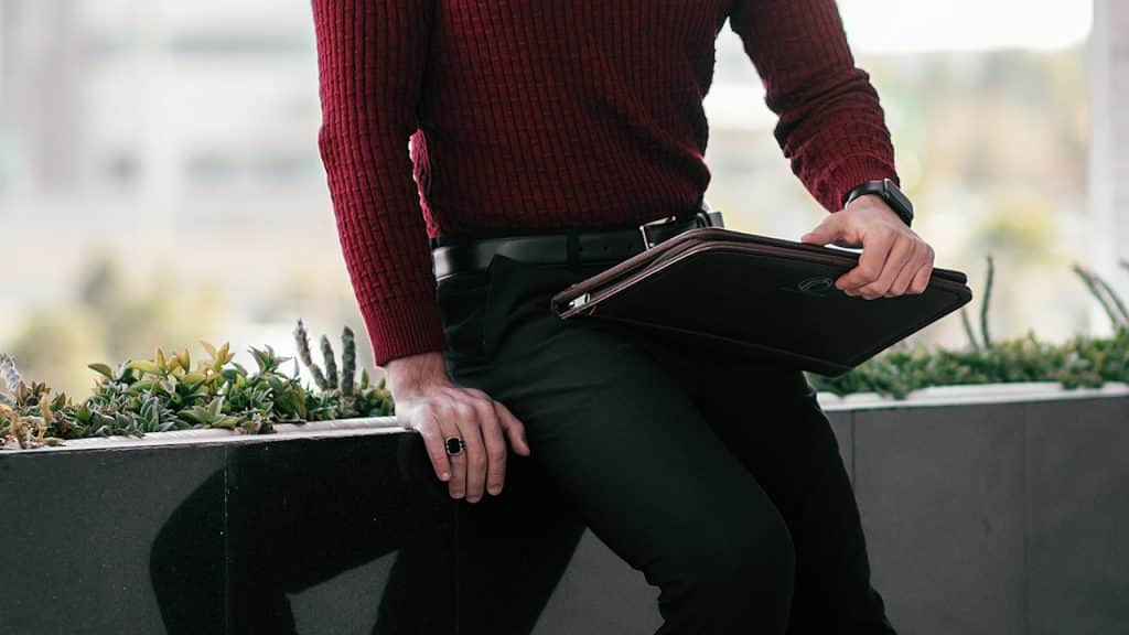 A man wearing a sweater over tailored pants.