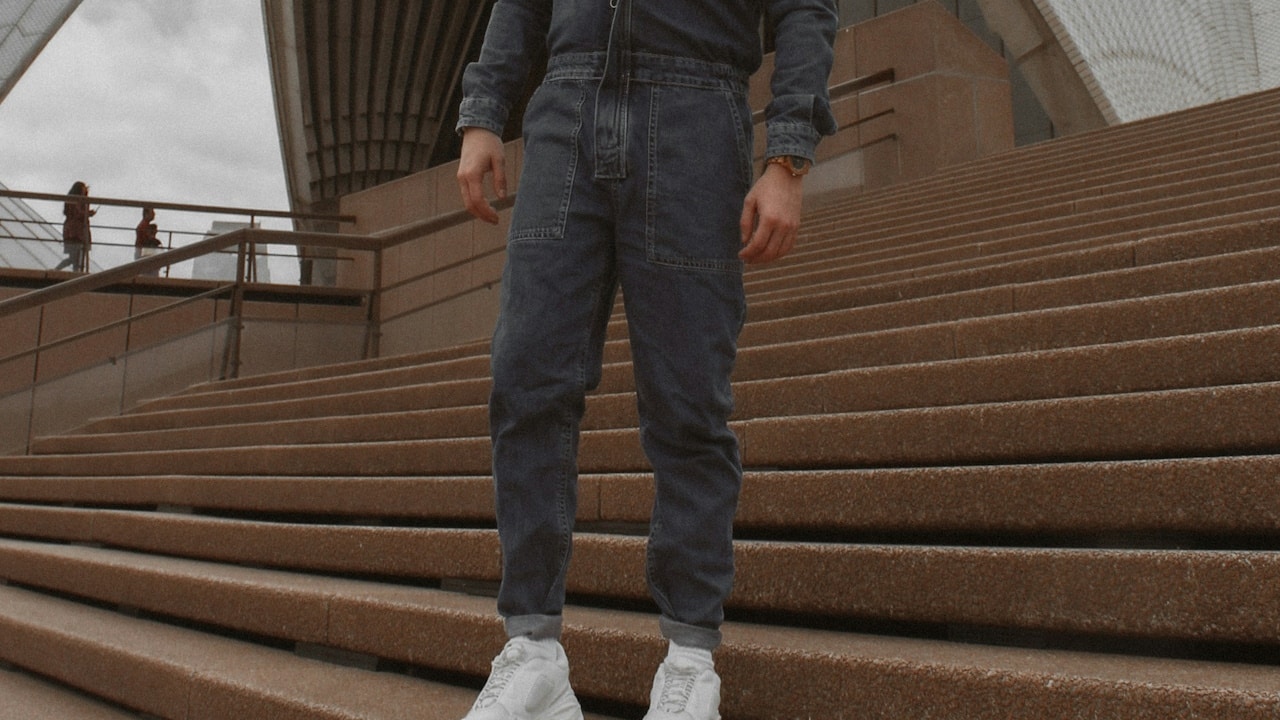 A man wearing a jumpsuit and standing on stairs.