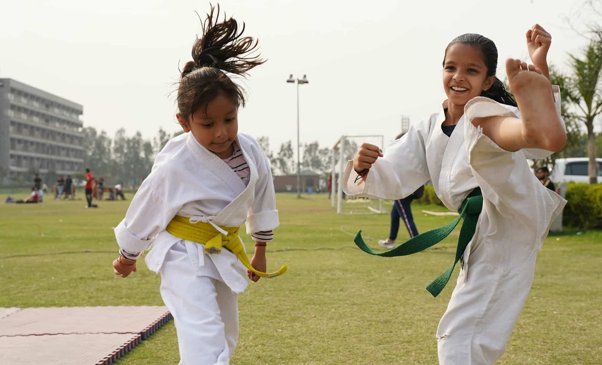 A pair of girls practicing martial arts outdoors.