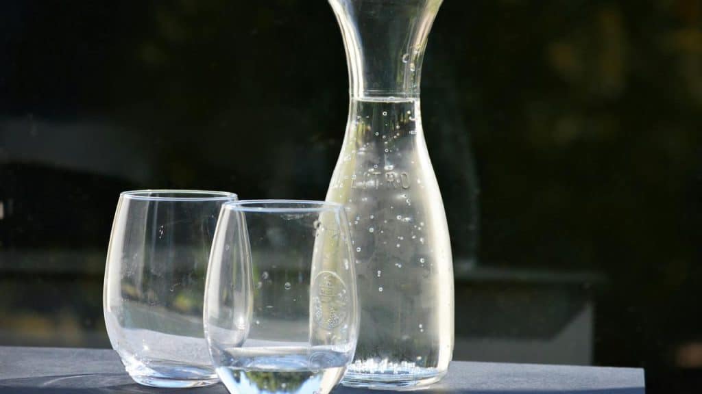 A glass carafe and two glasses filled with water.