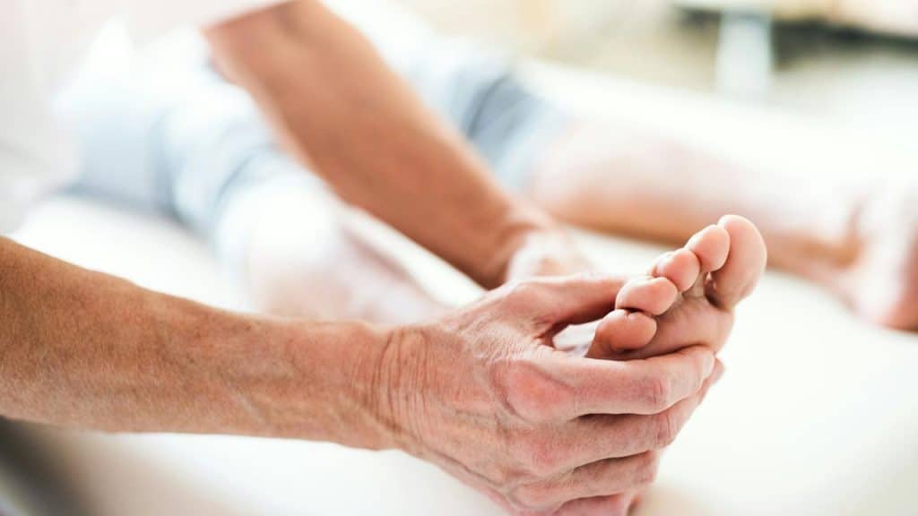 A person stretches by holding their foot.