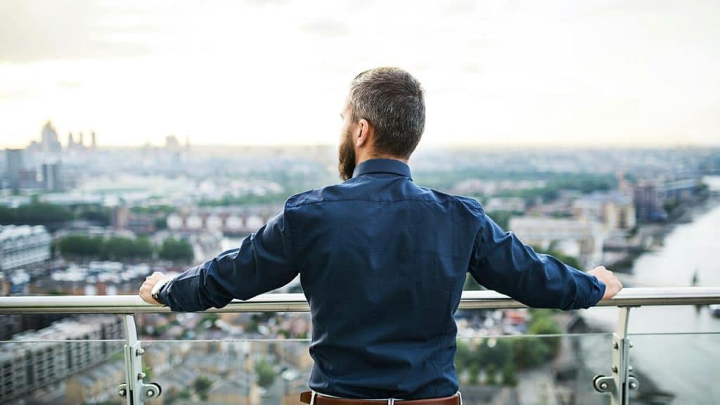 A man standing on a balcony overlooking a city.