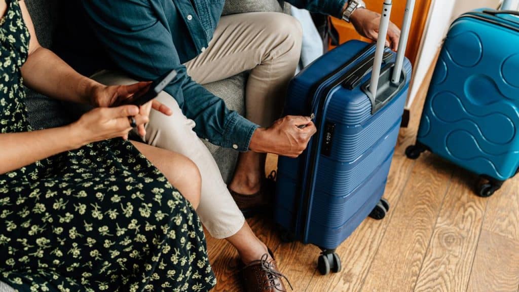 A couple sitting with suitcases, preparing for travel.
