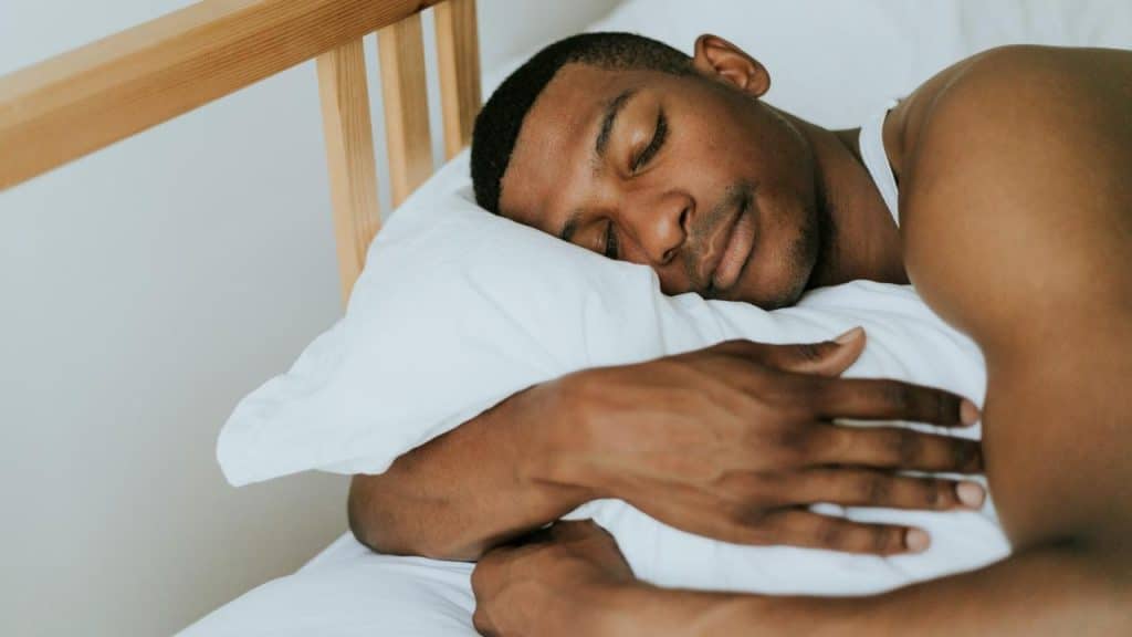 A man sleeping peacefully on a white pillow.