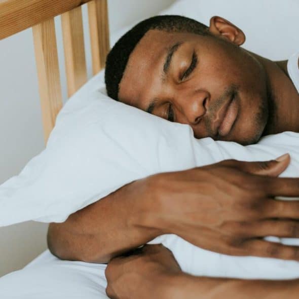 A man sleeping peacefully on a white pillow.