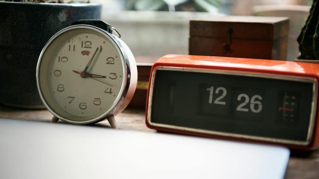 A vintage alarm clock and a retro flip clock on a wooden surface.