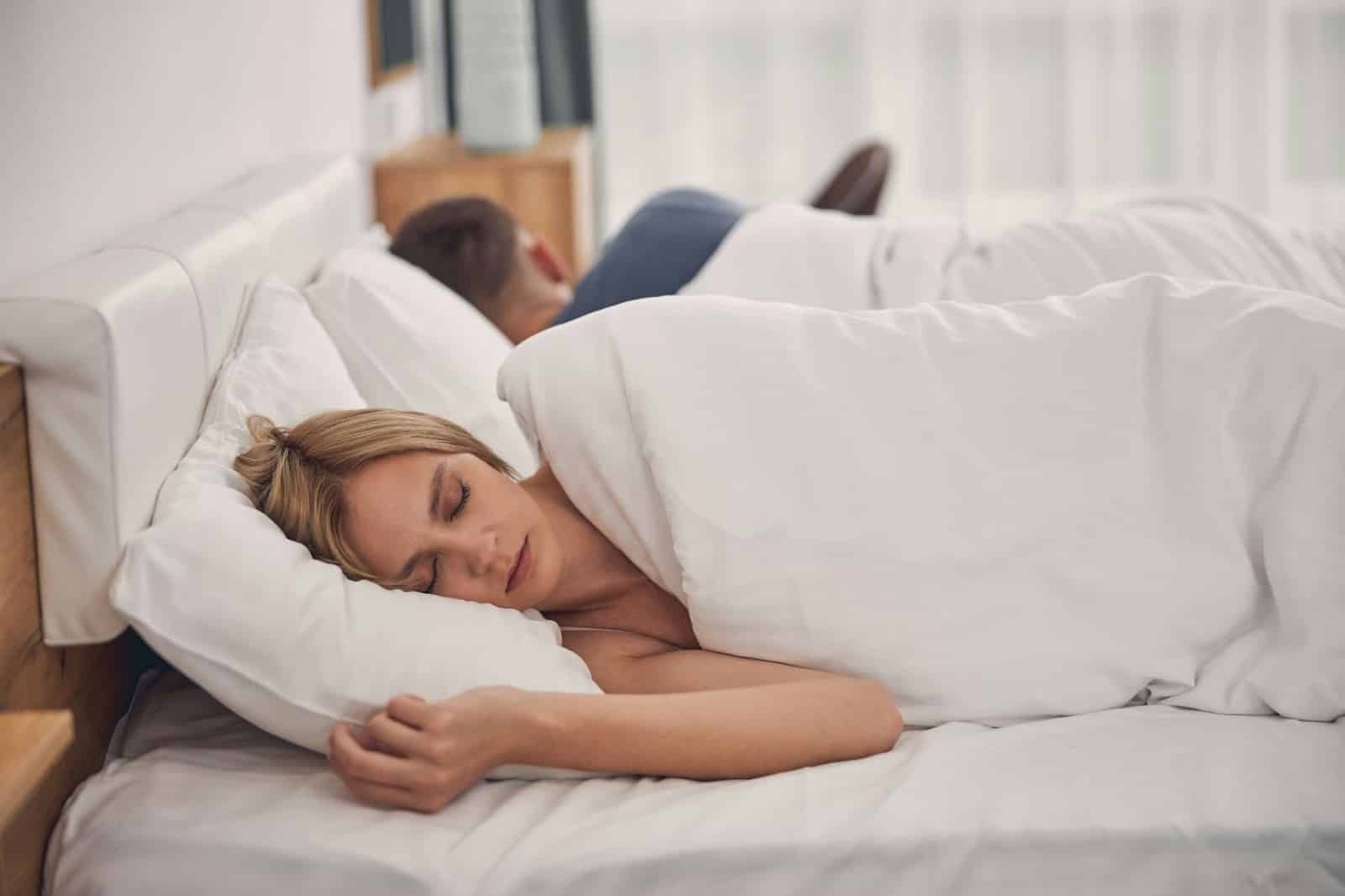 A man and woman sleeping but facing away from each other.