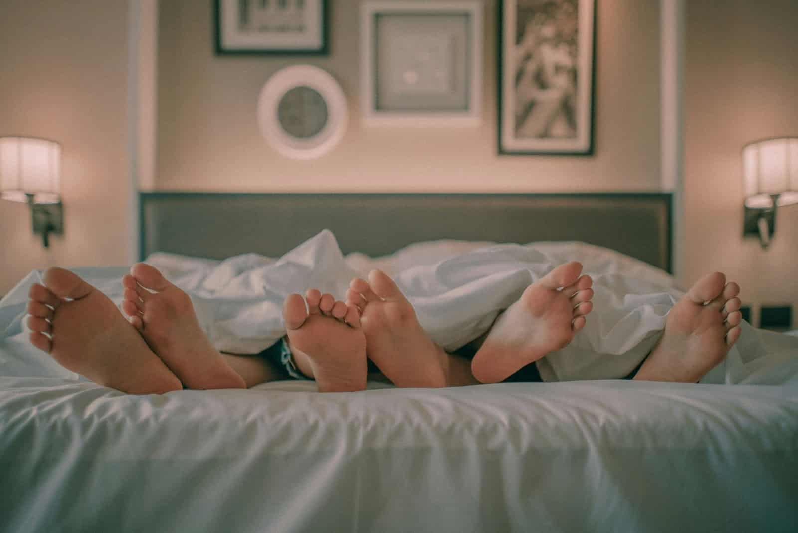 A man and woman’s feet under a blanket.