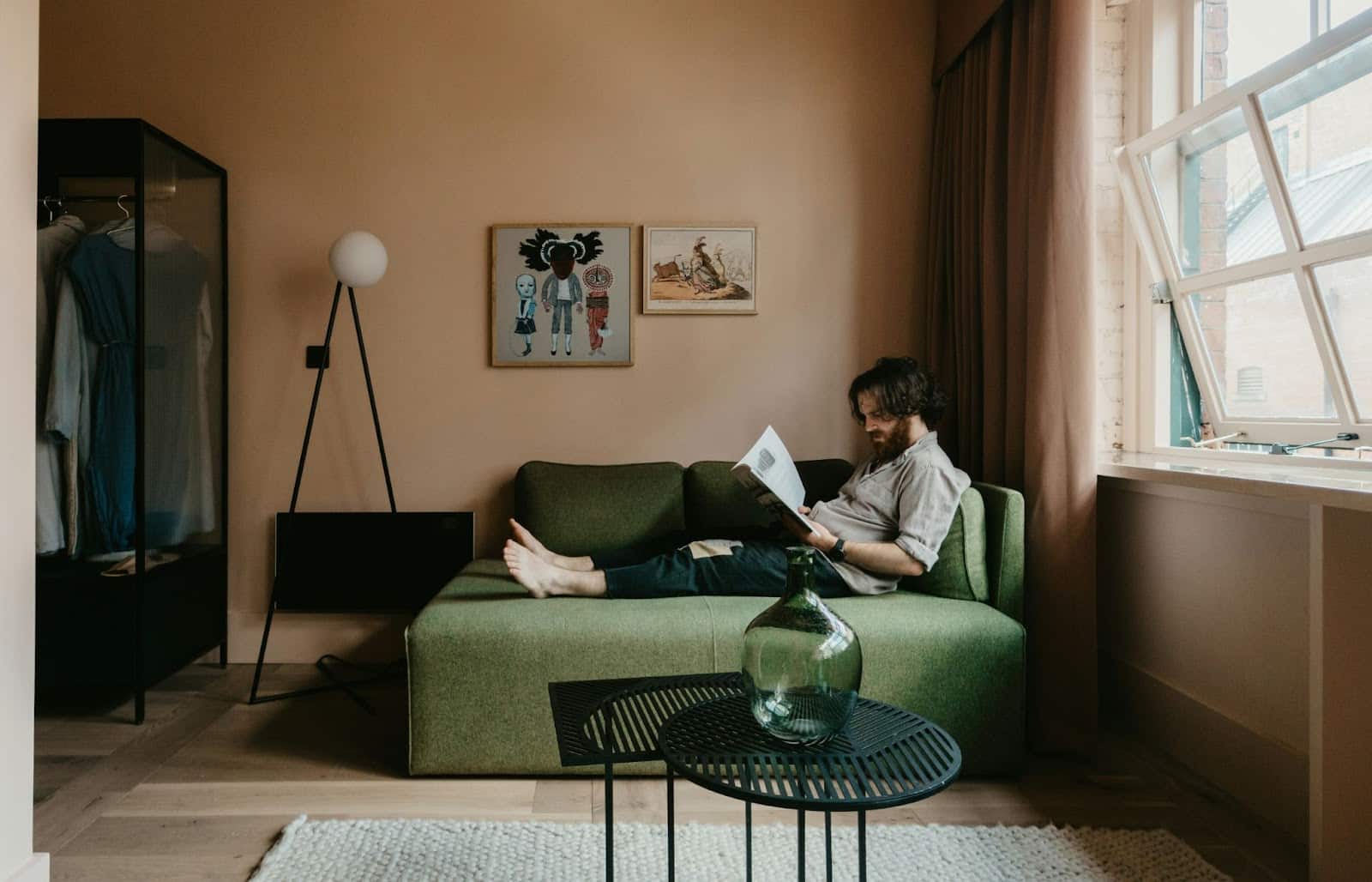 A man sitting on couch reading a book.