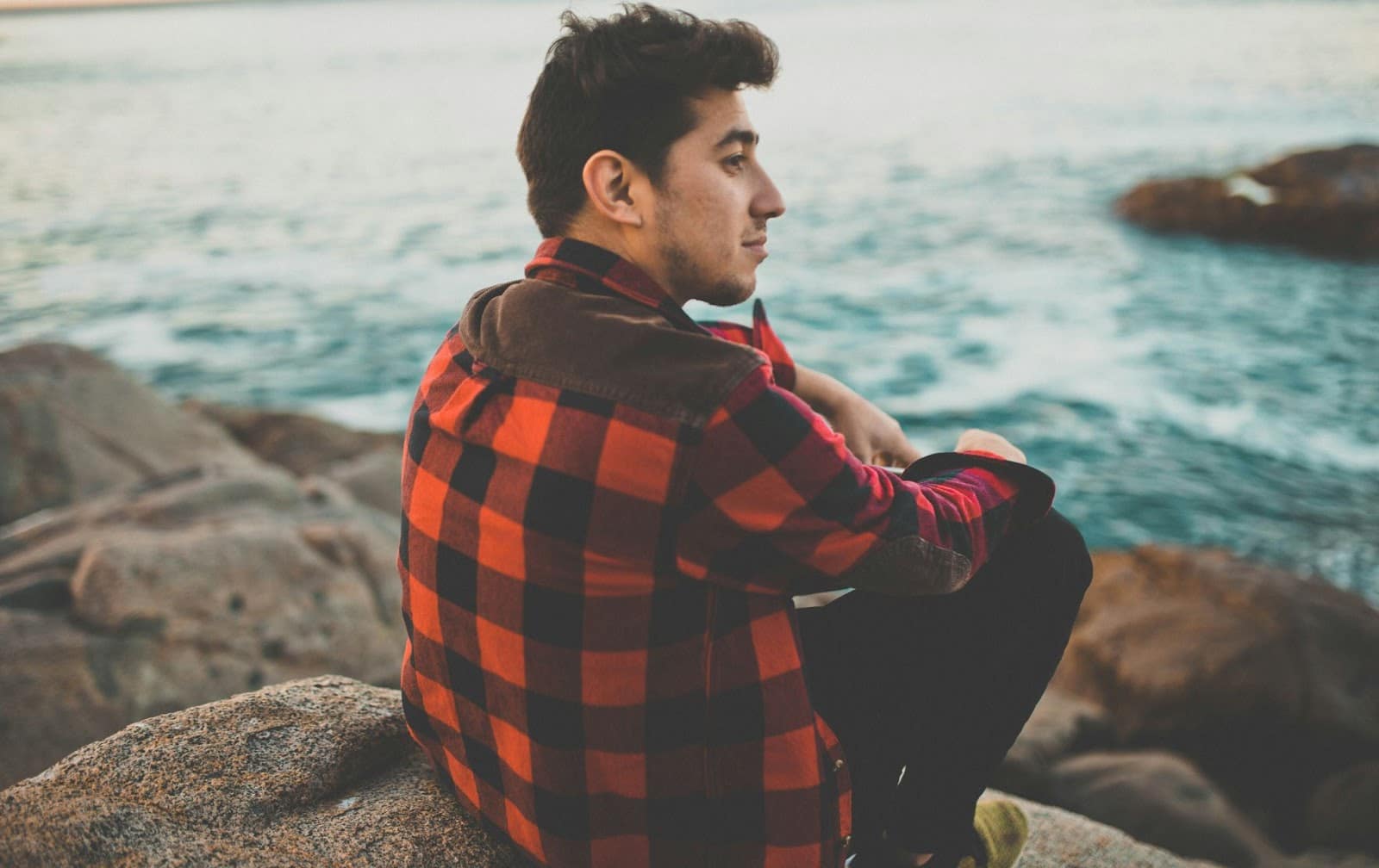 A man sitting alone on the rocks.
