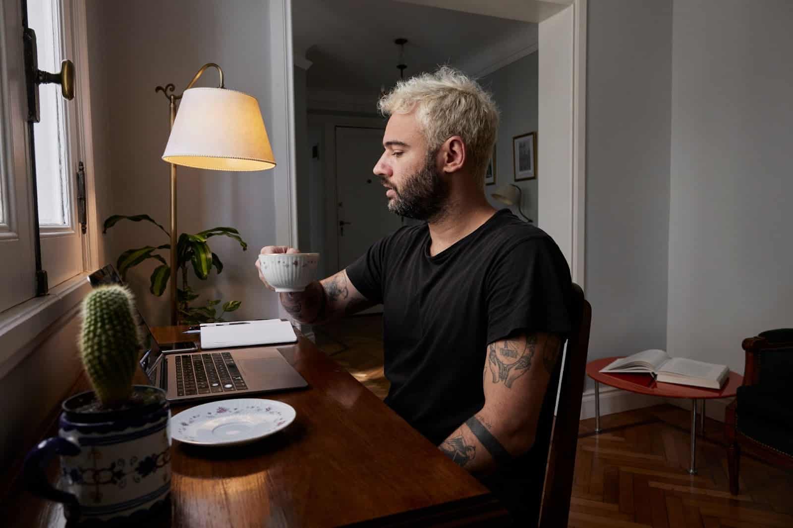 A man drinking coffee while using laptop.