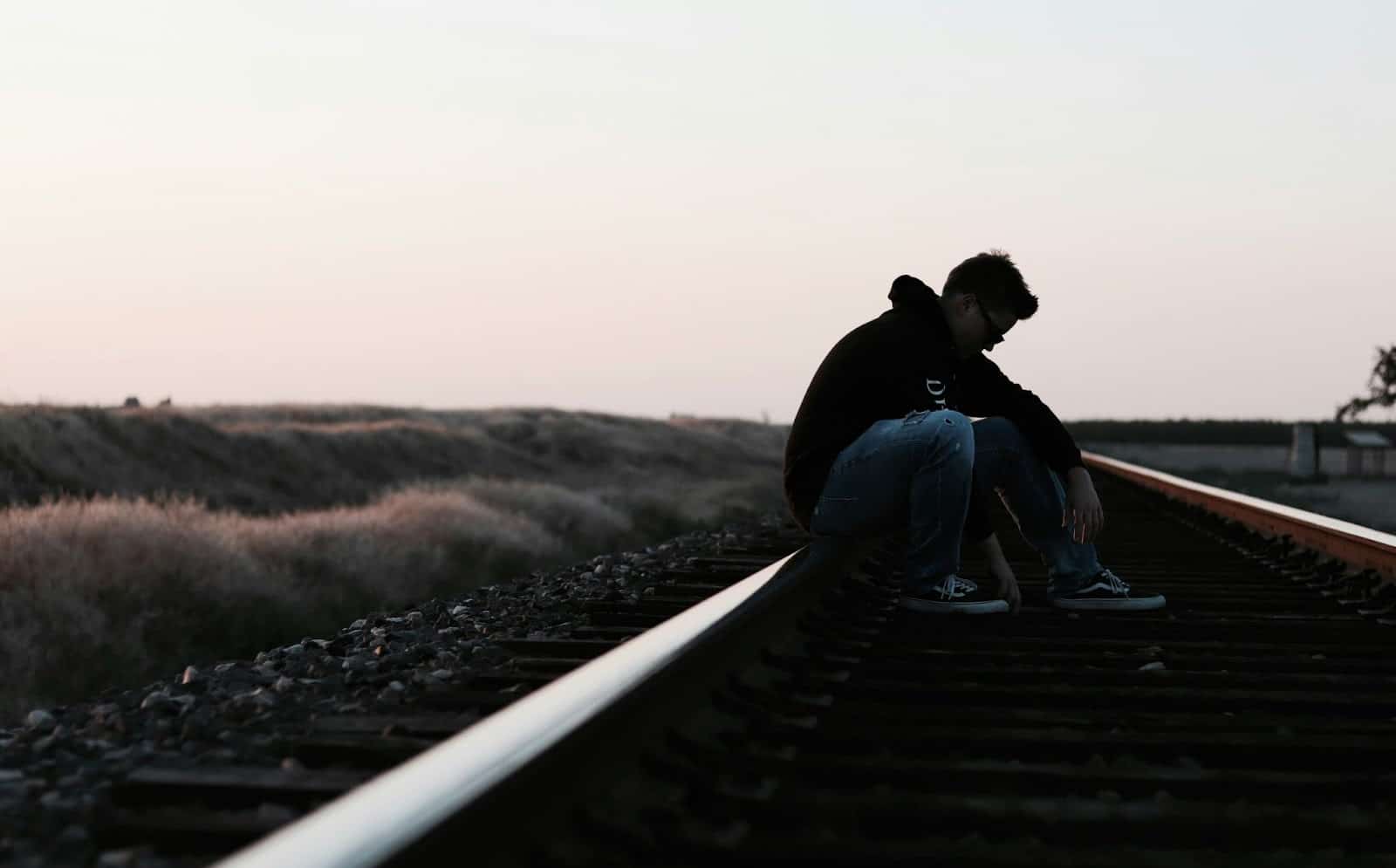 A man sitting on a railway alone.