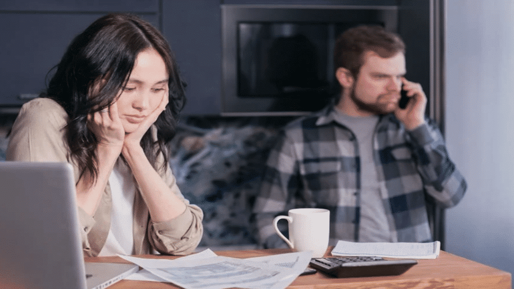 A woman looking sad while her husband is on the phone.