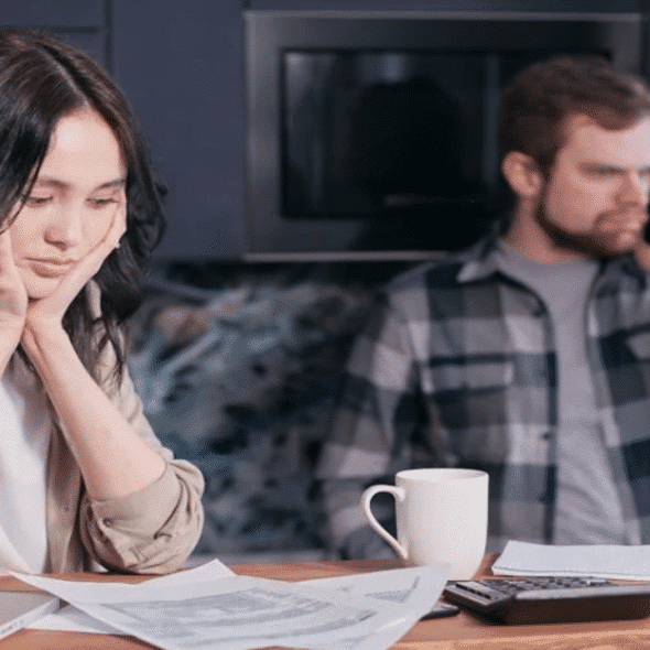A woman looking sad while her husband is on the phone.