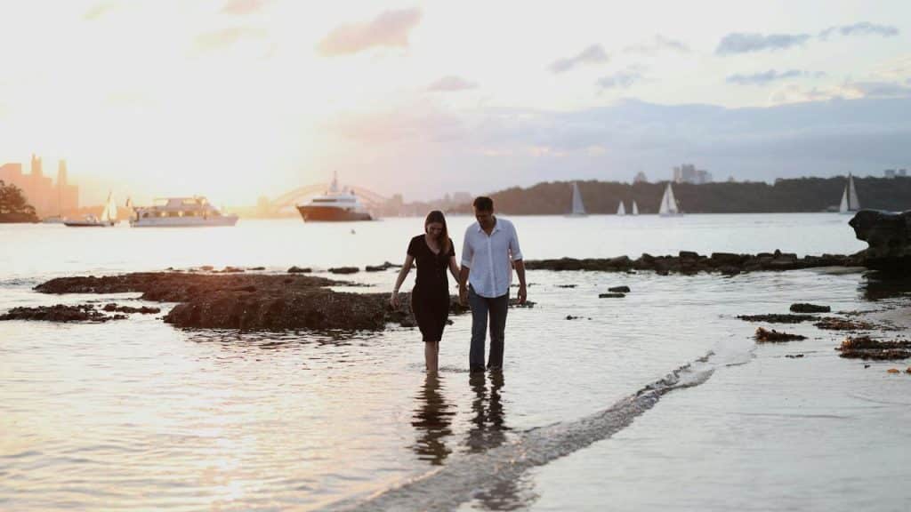 A couple walking along the beach at sunset.
