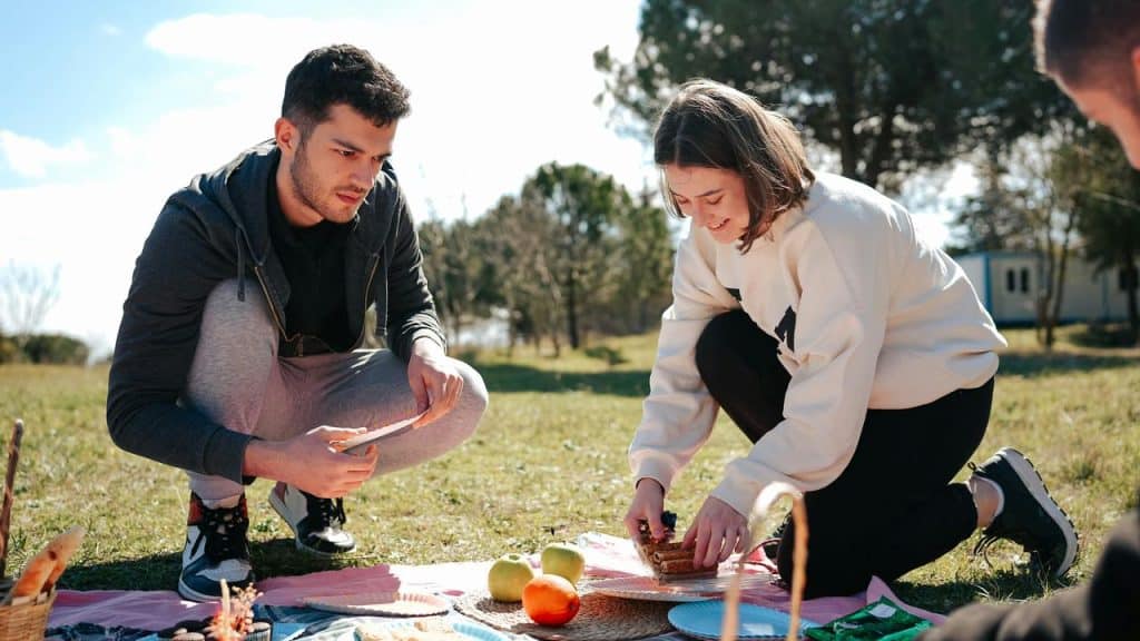 A couple setting up food during a picnic.