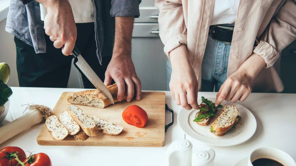 A couple preparing sandwiches together.