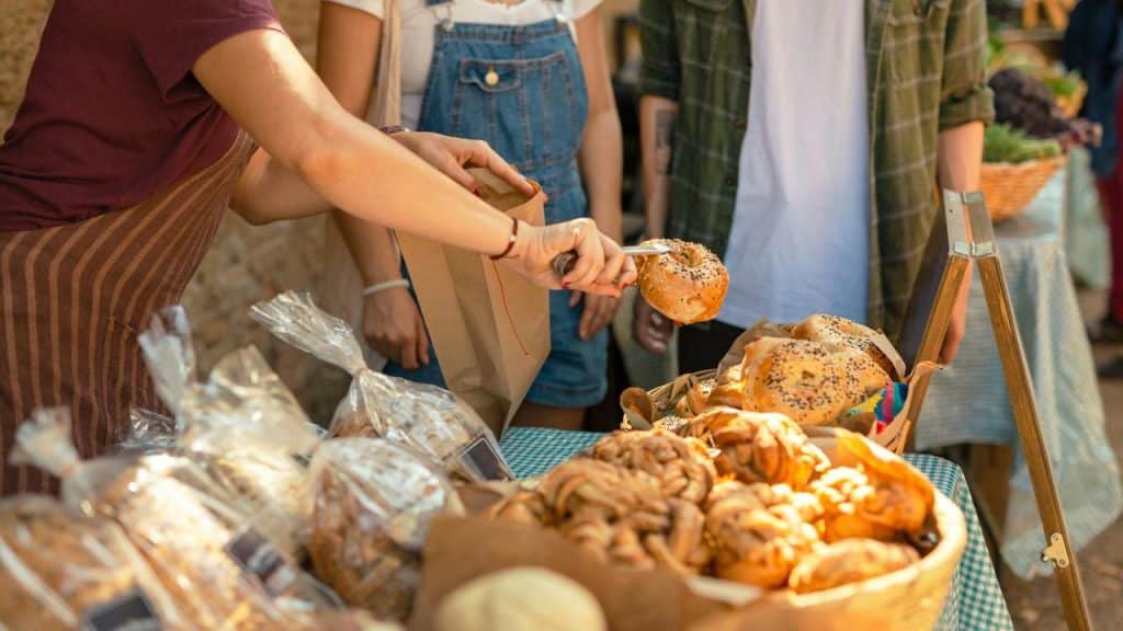 A vendor bagging bread at an outdoor market.