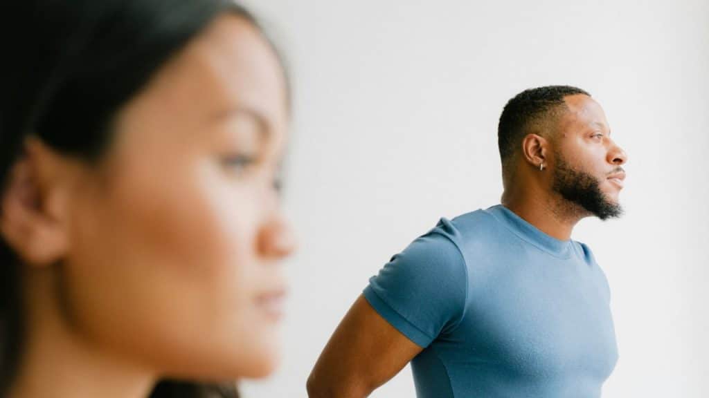 A focused image of a man looking away from a blurry, out-of-focus woman.