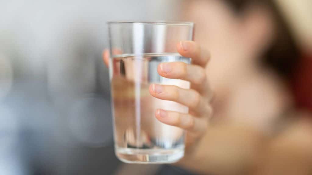A person's hand holding a glass of water.