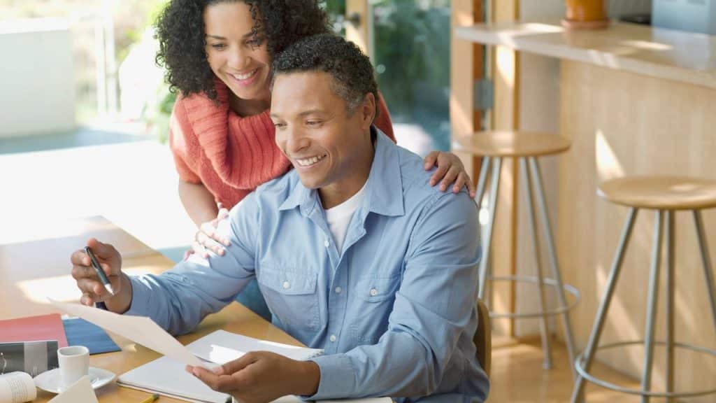 A smiling couple reviewing documents at a table.