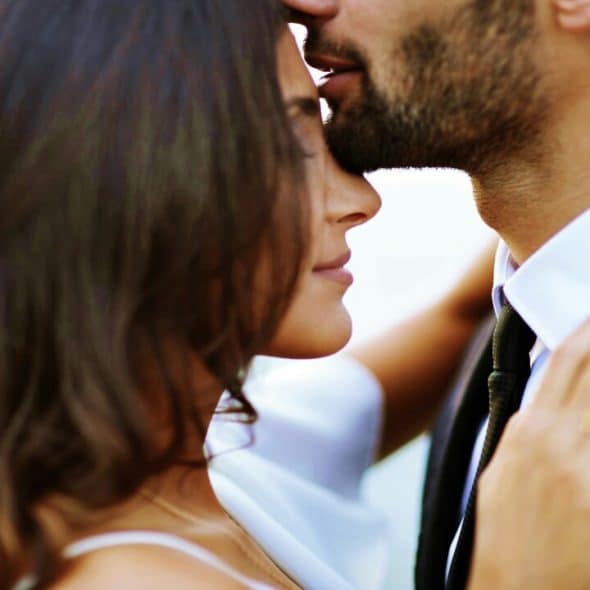 A man kissing a woman on the forehead
