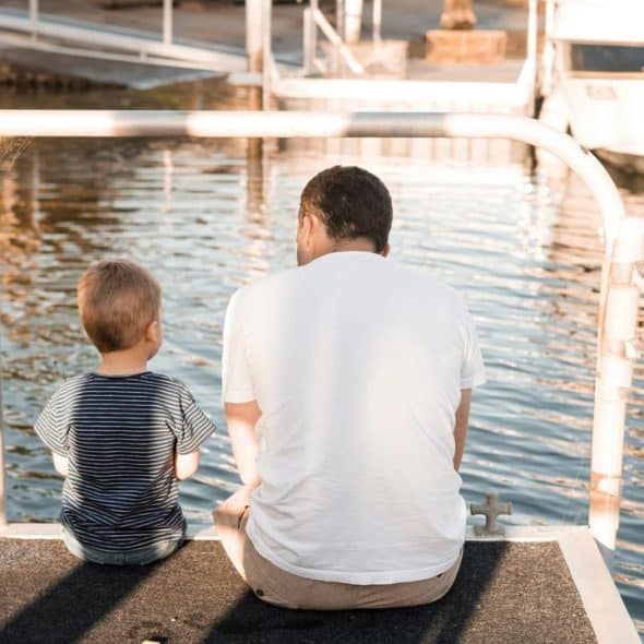 A man and a boy sit on a dock.