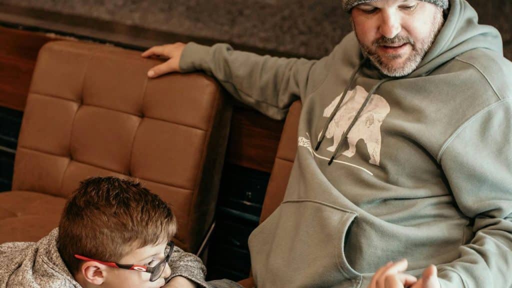 A man talks with a boy on a couch.