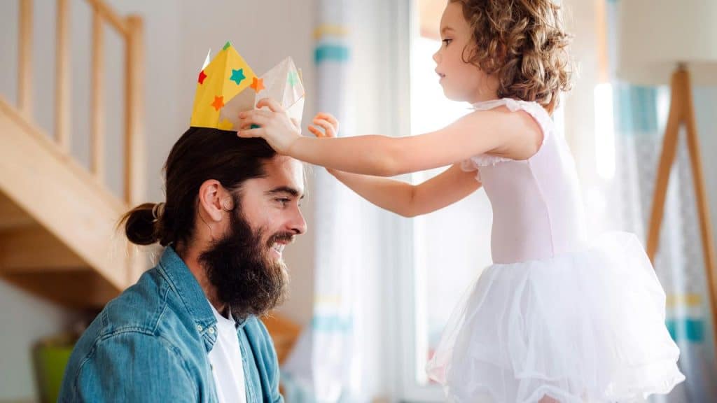 A girl puts a crown on her smiling dad.