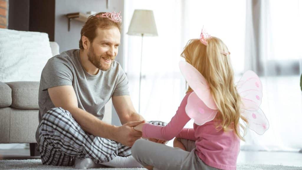 A dad and daughter play dressed as fairies.
