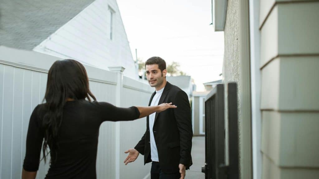A couple arguing outside by a gate.