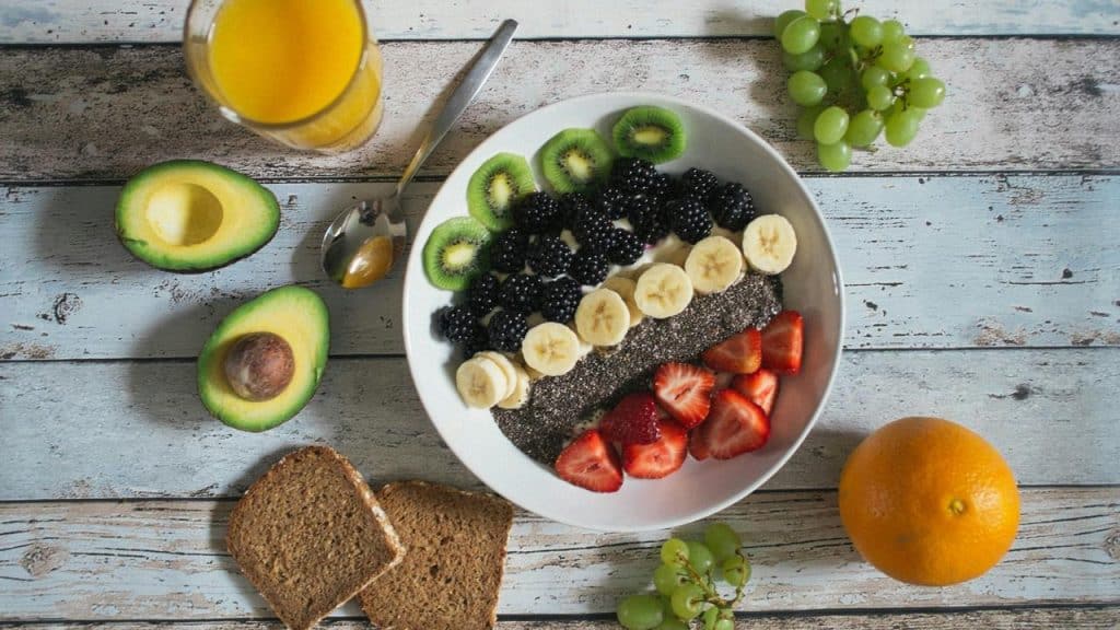 A bowl of fruit and chia seeds with toast and juice.