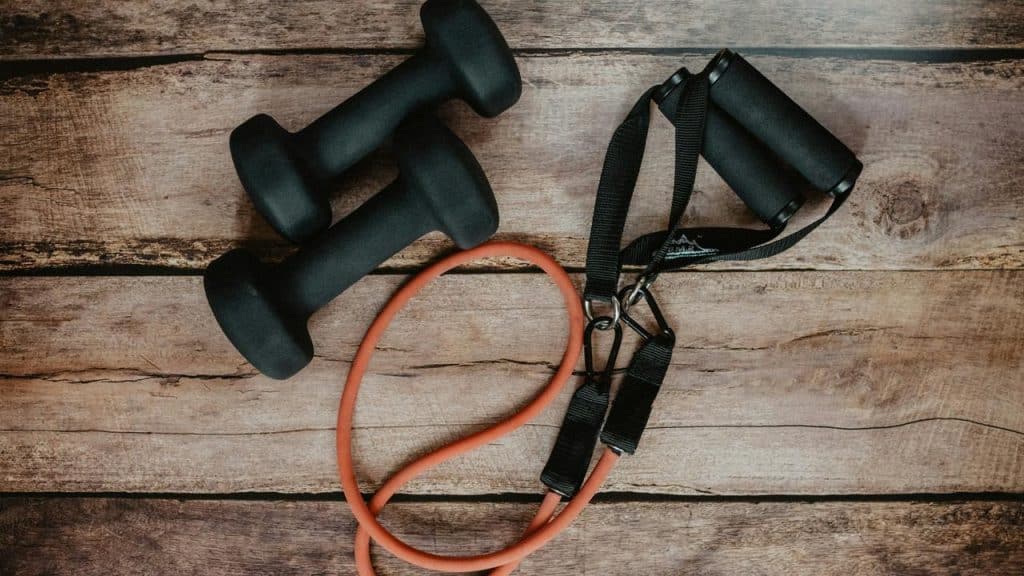 A pair of dumbbells and a resistance band on a wooden floor.
