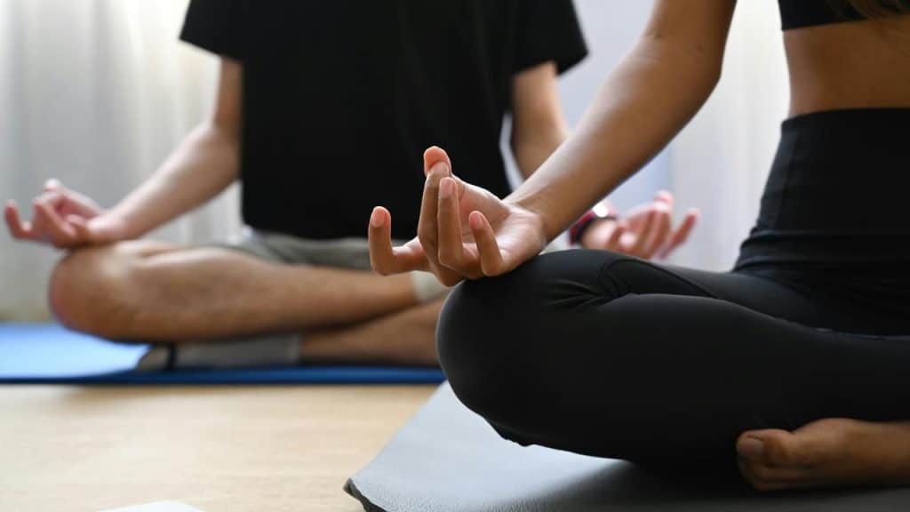 A man and woman meditating on yoga mats.
