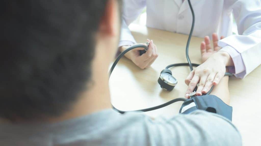 An individual having their blood pressure checked by a doctor.