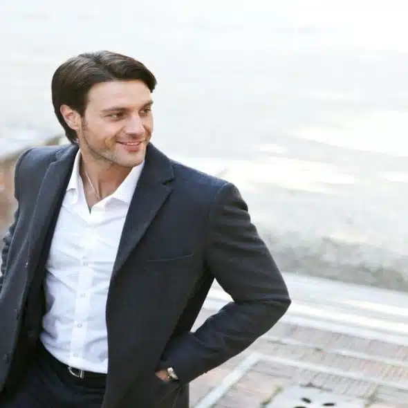 A man standing confidently outdoors.