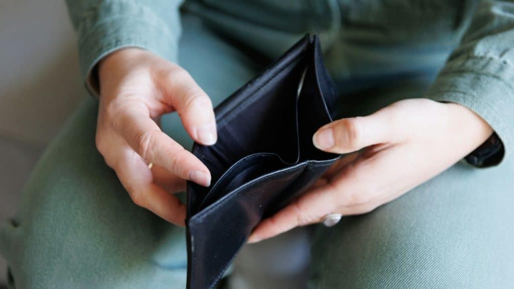 A person's hands hold an empty, open black wallet.