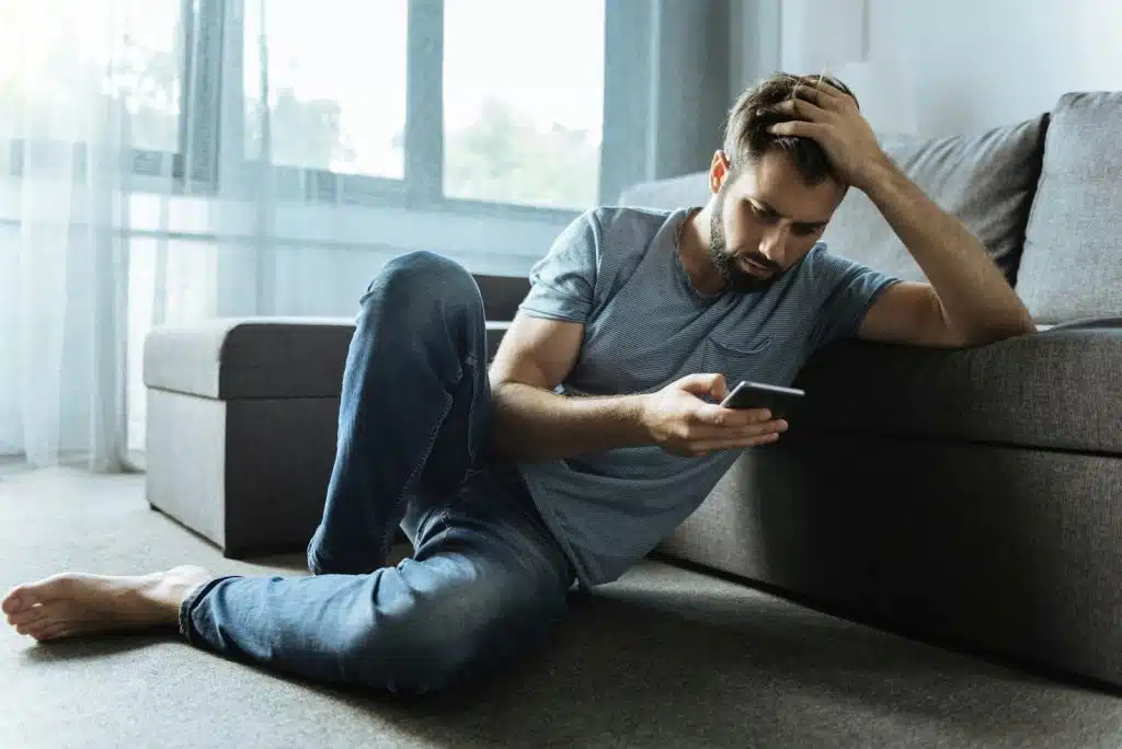 A man holding his head while sitting on the floor.