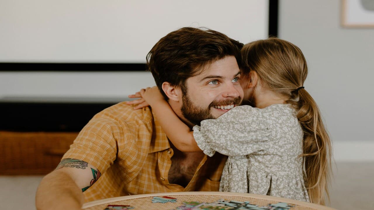 A man being hugged by his daughter.