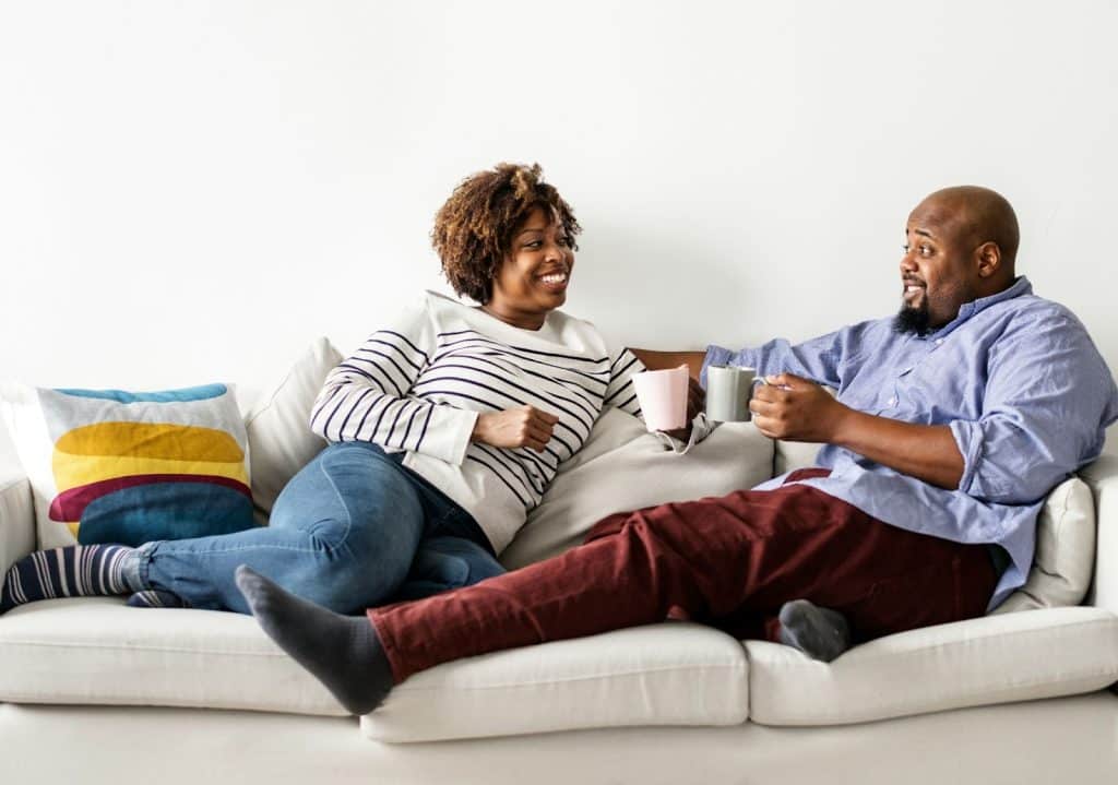 A man and woman on a couch while having conversation.