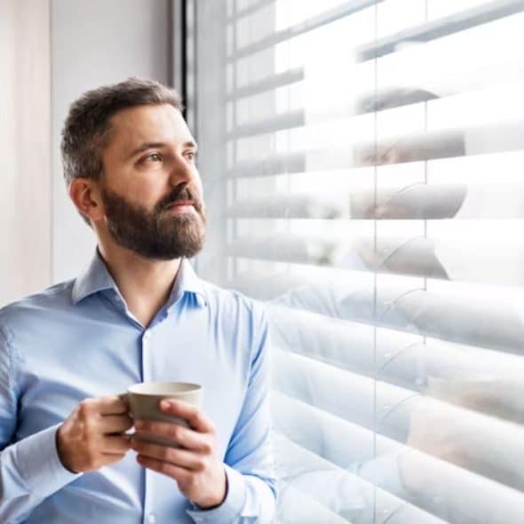 Man staring out a window deep in thought