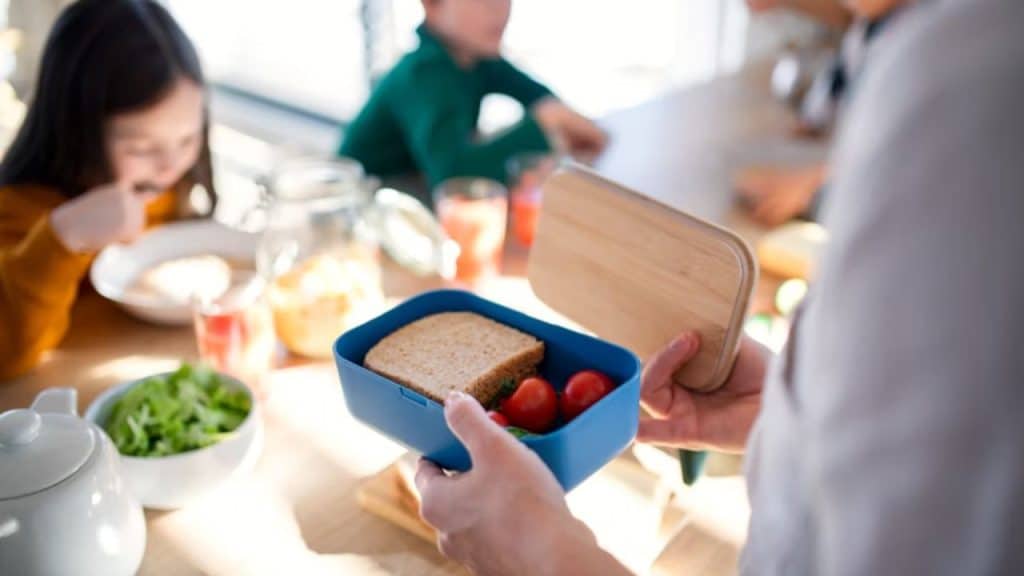 Man prepping a colorful, healthy lunchbox for kids